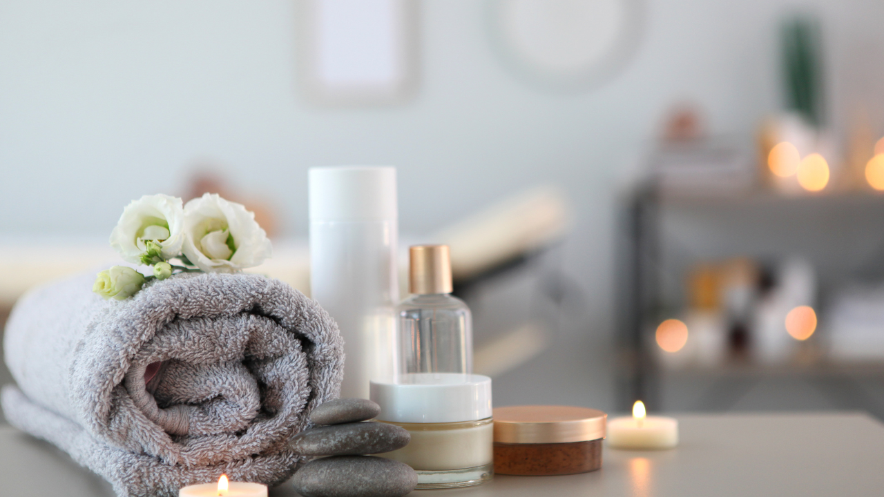 Serene med spa setting in Hayden, Idaho: rolled towel, flowers, skincare bottles, candles, and stones on a treatment table. at North Idaho Med Spa in Hayden