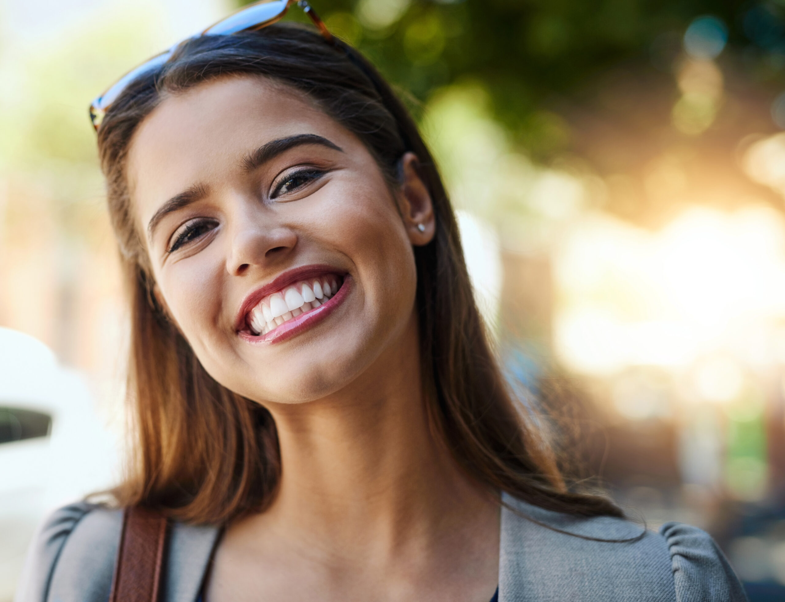 A young woman with glowing skin smiles outdoors, showcasing radiant results from RF microneedling at Hayden Idaho med spa. at North Idaho Med Spa in Hayden