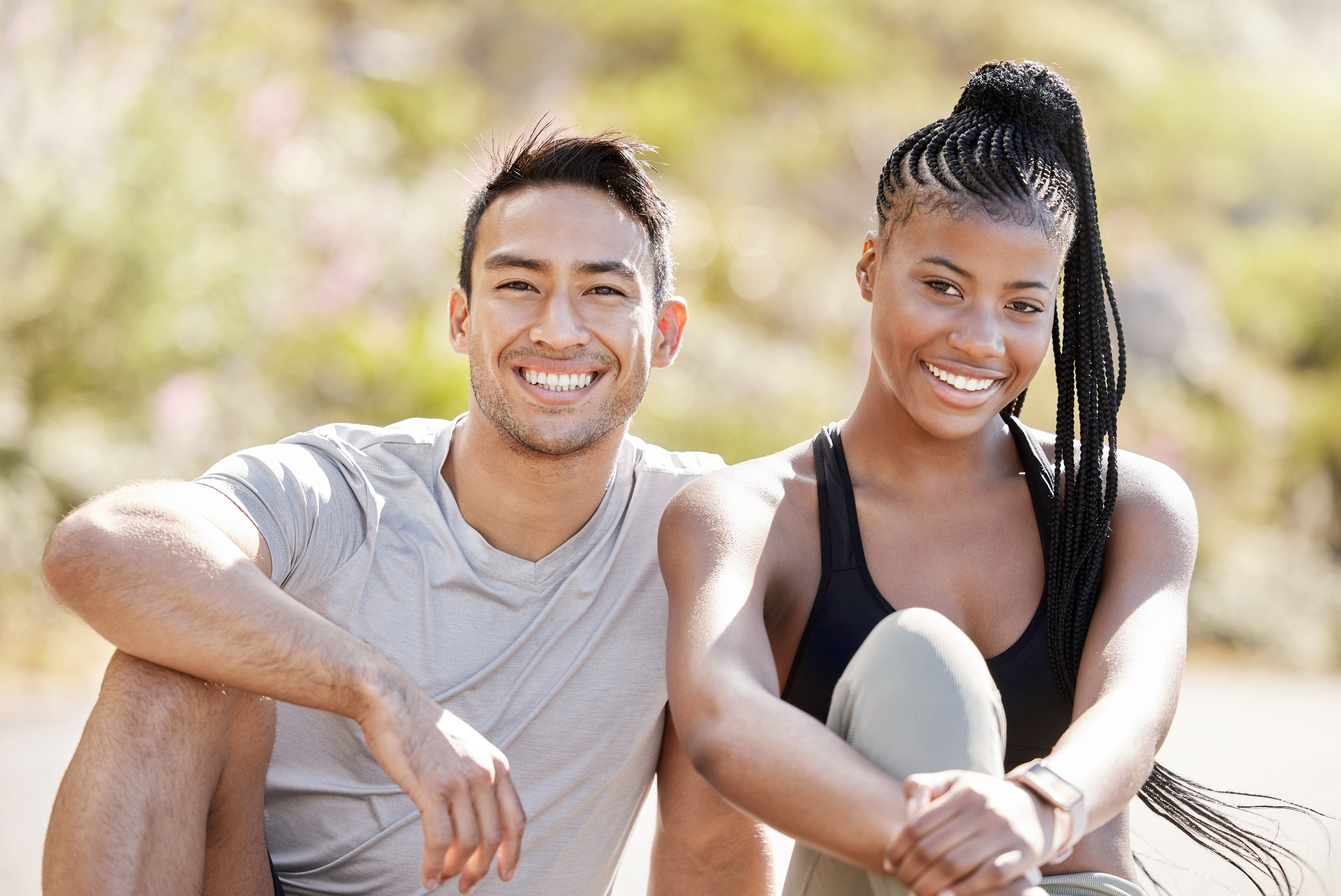 Two people in athletic wear smile outdoors with lush greenery behind them, reflecting the active lifestyle near Hayden ID med spa. at North Idaho Med Spa in Hayden