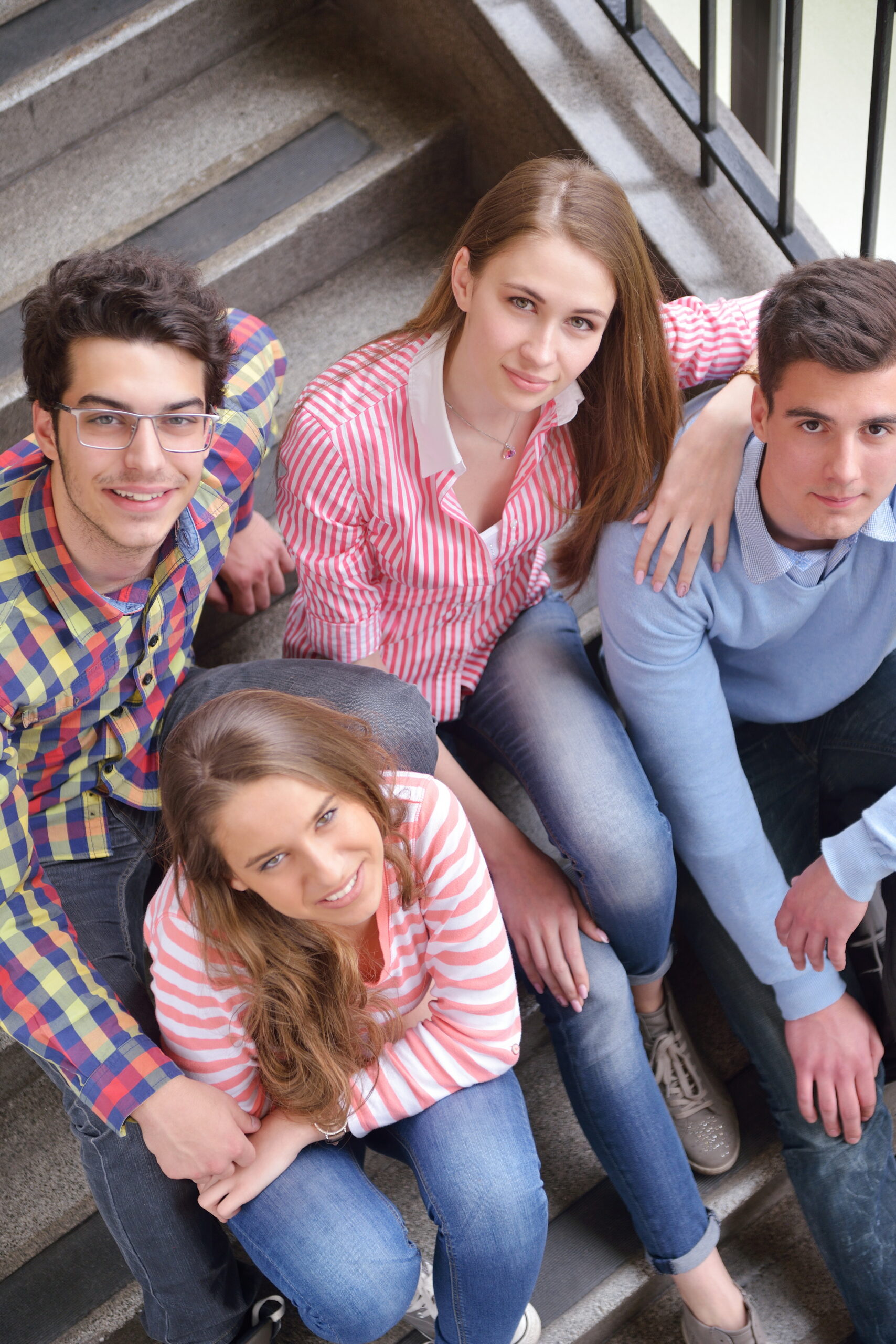 Four young adults relax on stairs, smiling after IV therapy at a Hayden, Idaho med spa, casually dressed in jeans and shirts. at North Idaho Med Spa in Hayden