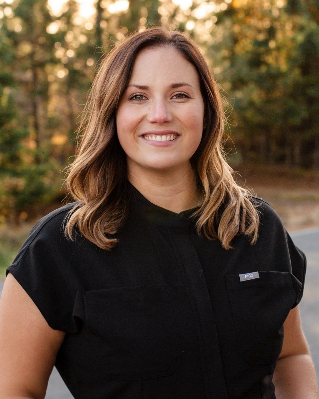 A woman with brown hair smiles confidently outdoors, showing glowing skin after RF microneedling at a Hayden Idaho med spa. at North Idaho Med Spa in Hayden