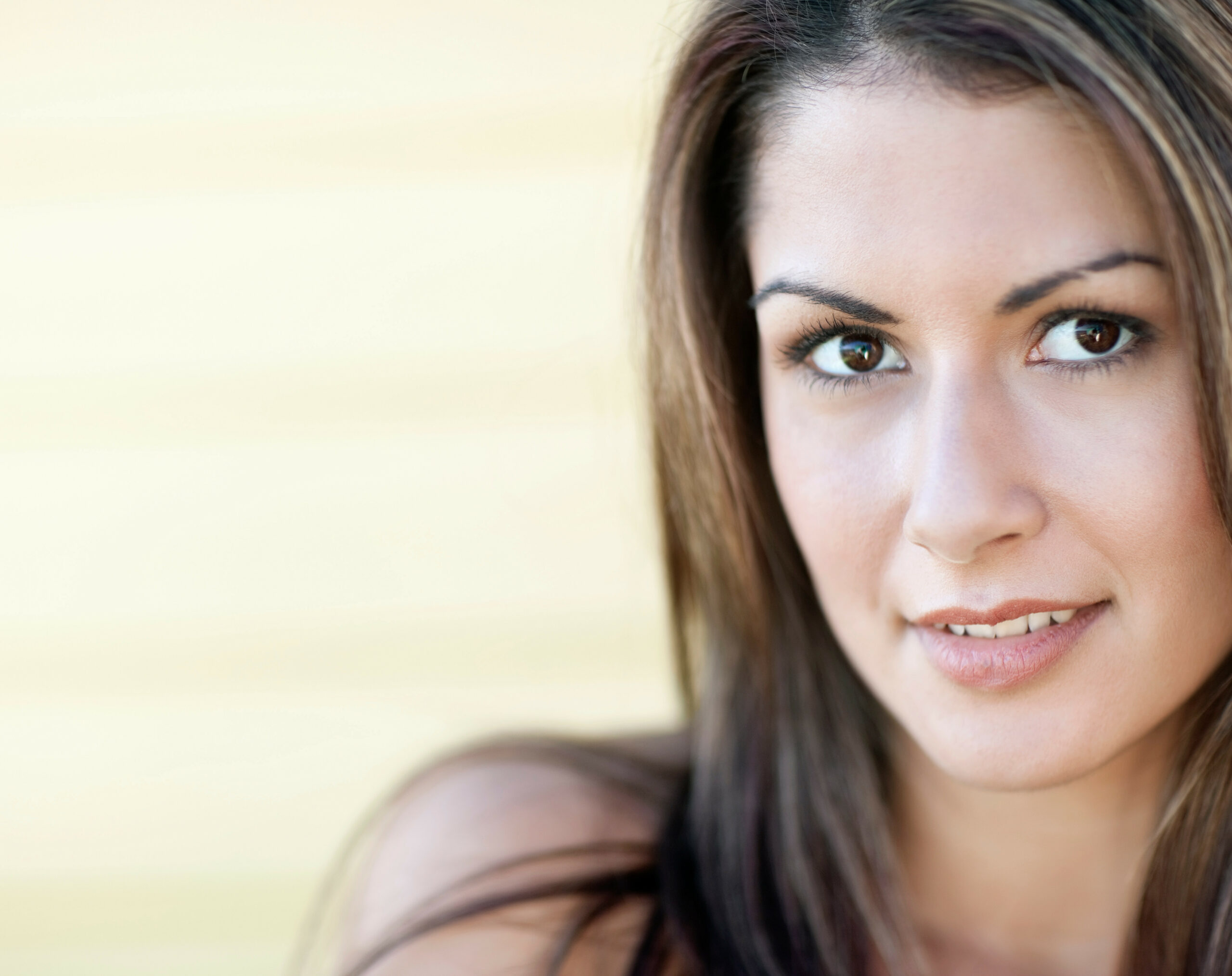 Smiling woman with long brown hair and brown eyes at med spa in Hayden Idaho, warm inviting background, relaxed skincare atmosphere. at North Idaho Med Spa in Hayden