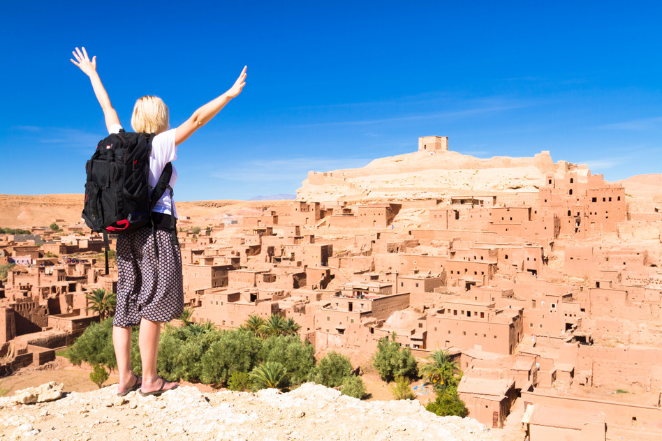 How to Decrease the Risk of Infection While Traveling Abroad Adventurous woman arms reised in front of Ait Benhaddou, fortified city, kasbah or ksar, along the former caravan route between Sahara and Marrakesh in present day Morocco.